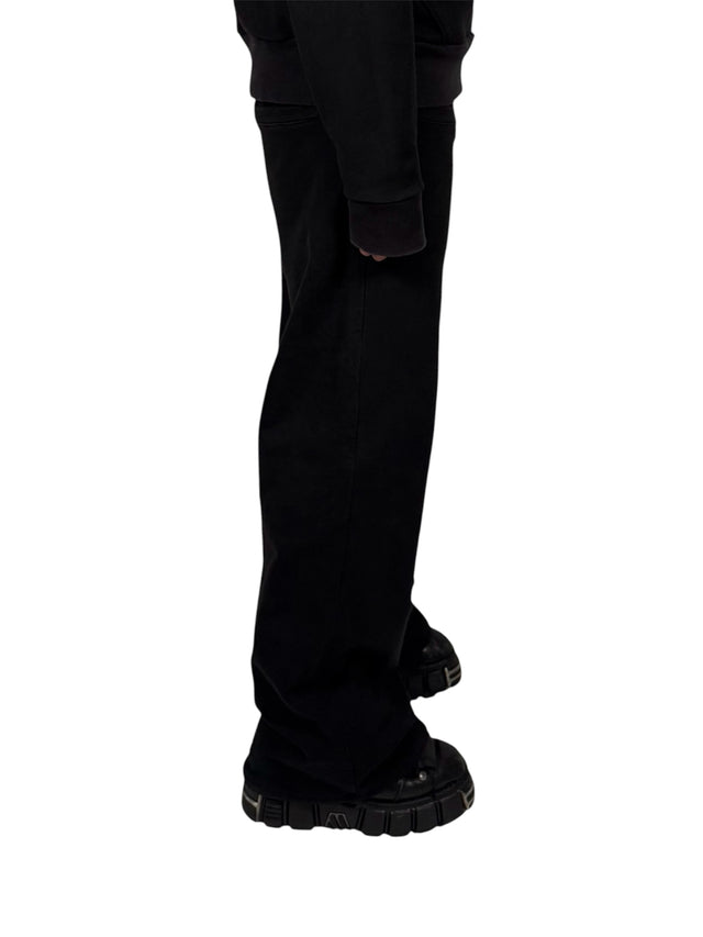 Side view of a model wearing the LOVANT black sweats with the black LOVANT raglan hoodie, showing the relaxed fit through the leg.