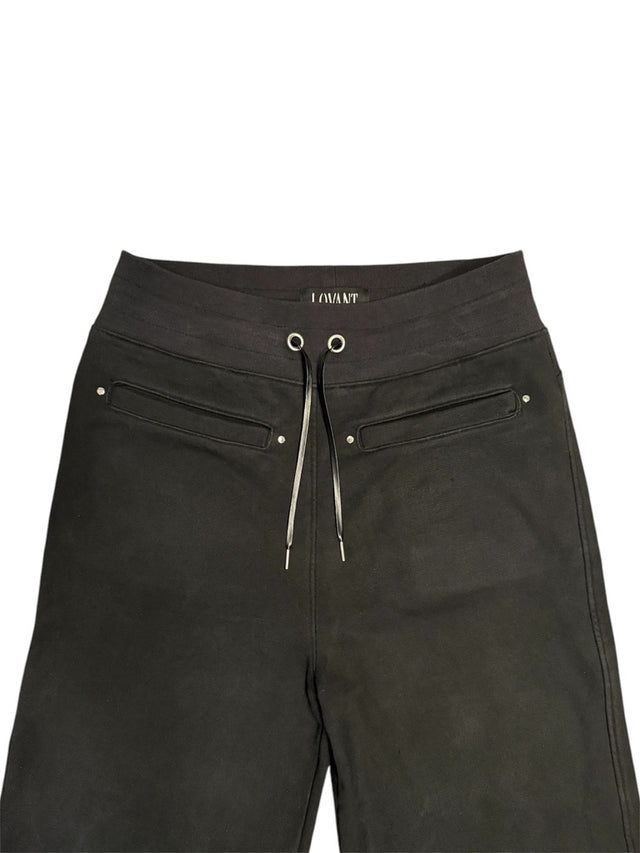 Close-up of the LOVANT black sweats, showing the ribbed waistband, LOVANT label, silver grommets, drawcord with metal tips and riveted welt pockets.