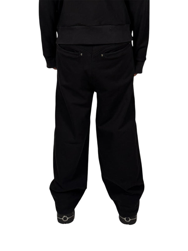 Back view of a model wearing the LOVANT black sweats, showing the riveted back pockets and wide leg.