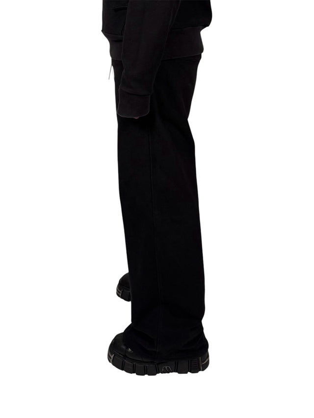 Side view of a model wearing the LOVANT black sweats, showing the wide leg and how it falls over chunky black boots.